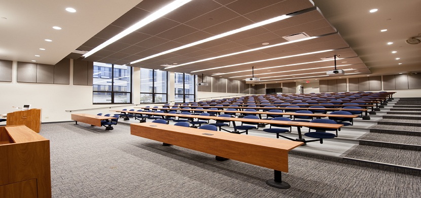 A University hall with acoustic ceiling, tables and chairs.