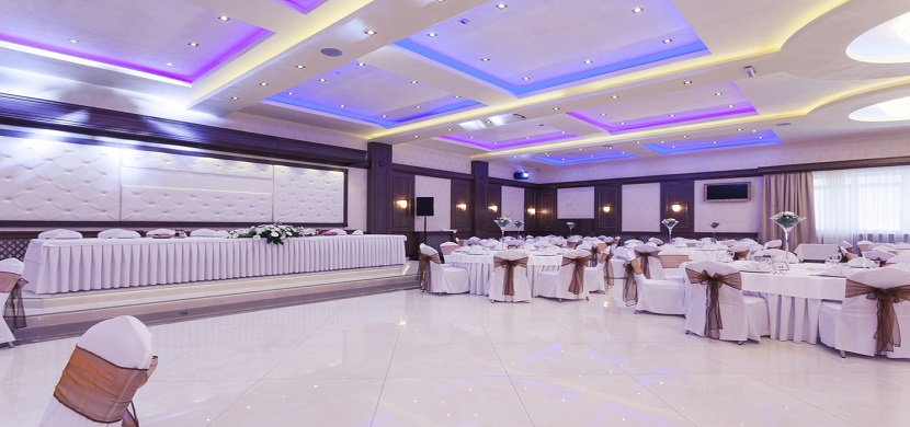 An event room with coffered ceiling and white tables and chairs.